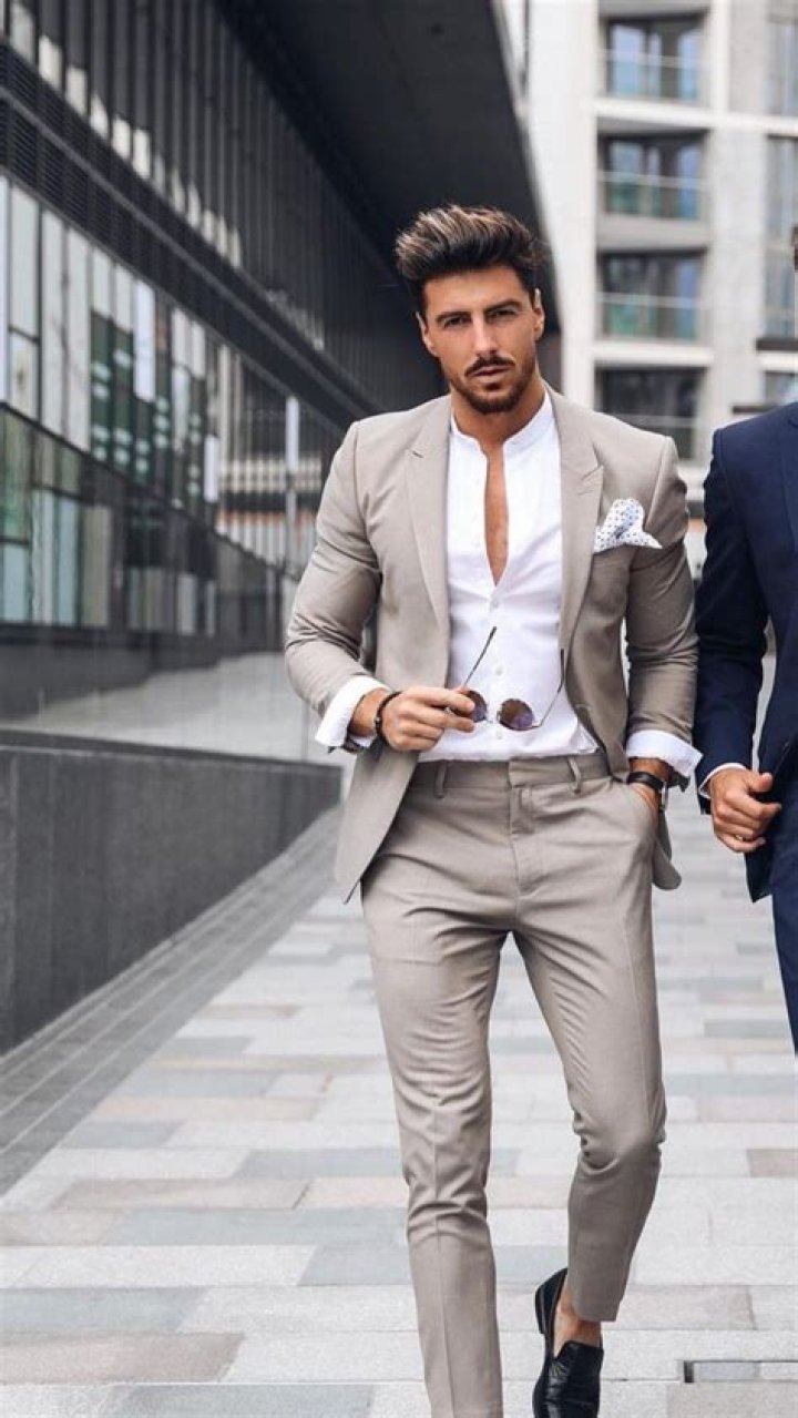 a man in a suit holding his hands on his chest and looking at the camera