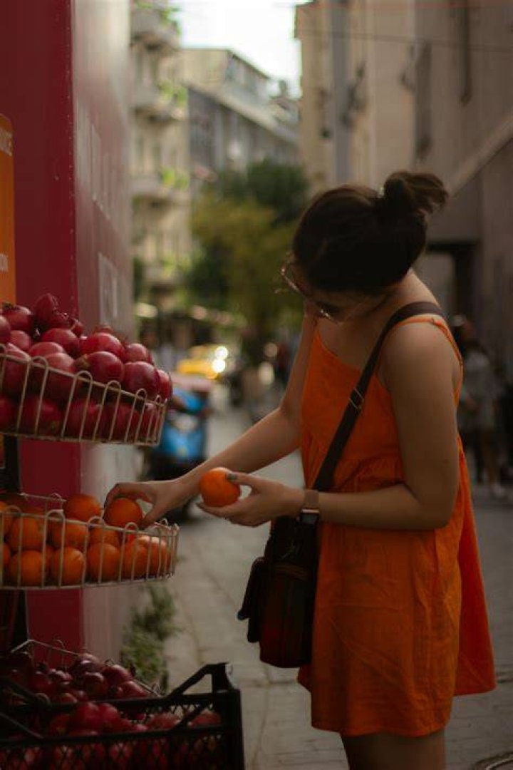 a woman in an orange dress is smiling and holding a green bag with her